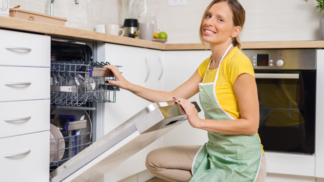 Kobieta otwiera zabudowana zmywarke w swojej kuchni